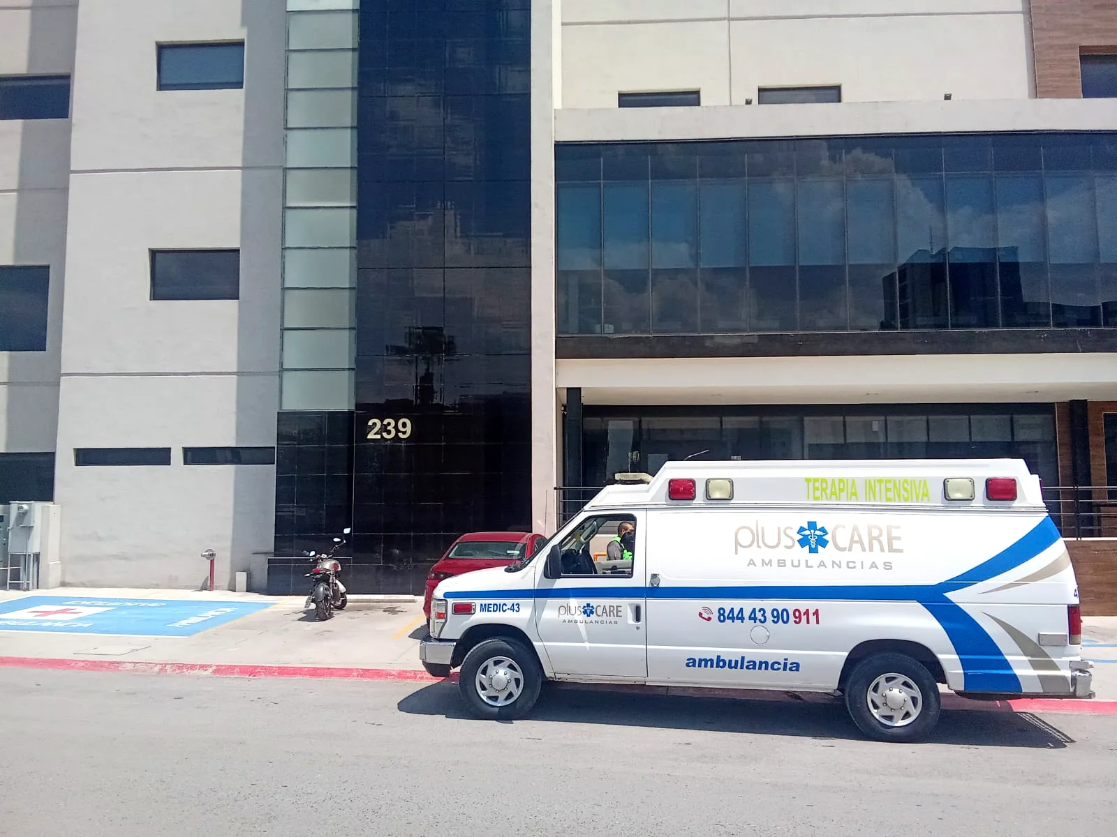 Ambulancia blanca Plus Care estacionada frente a un hospital
